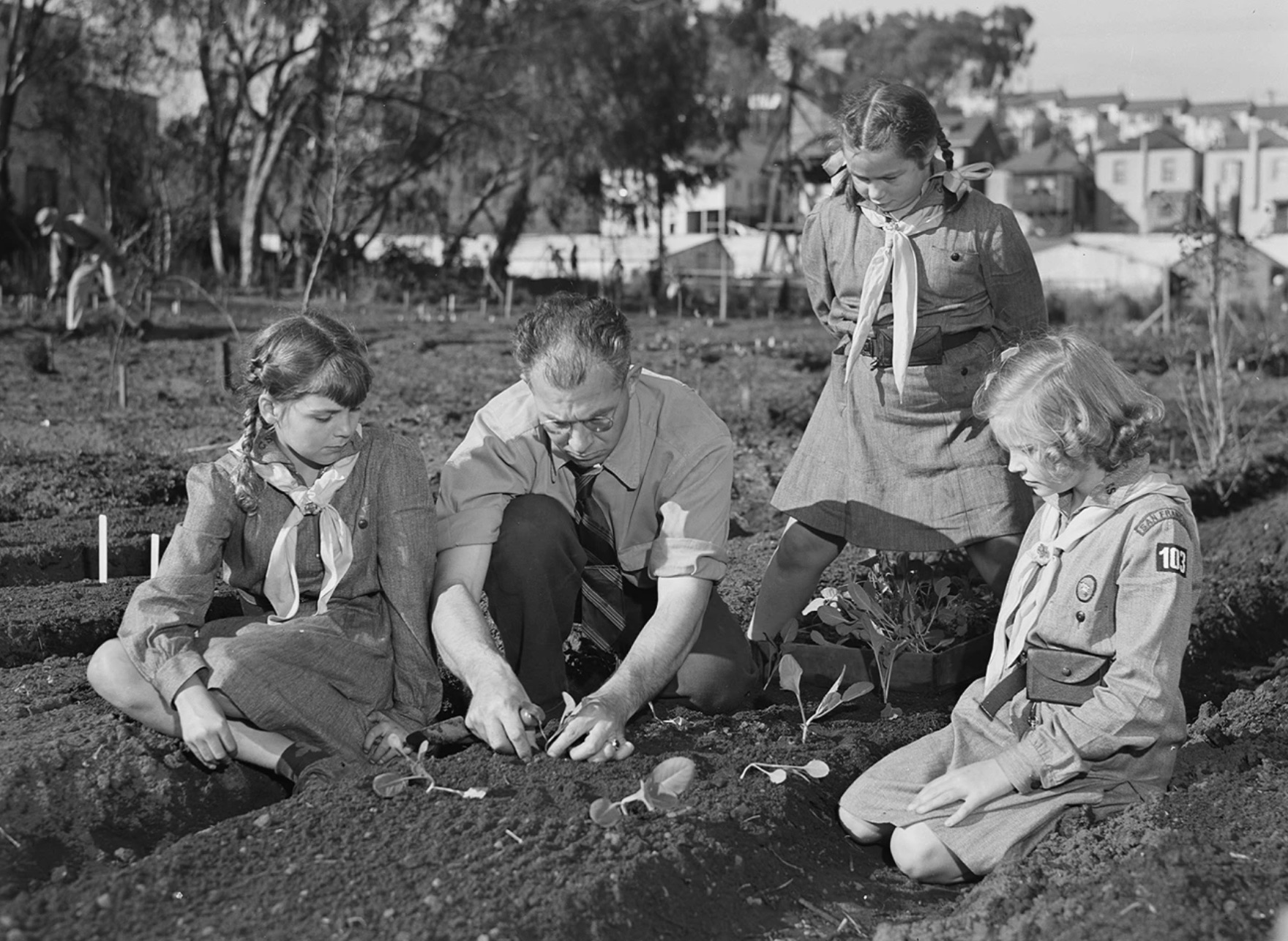 Harry Nelson gives his 10-year-old daughter and her Girl Scout friends some pointers in transplanting vegetables to the victory garden 